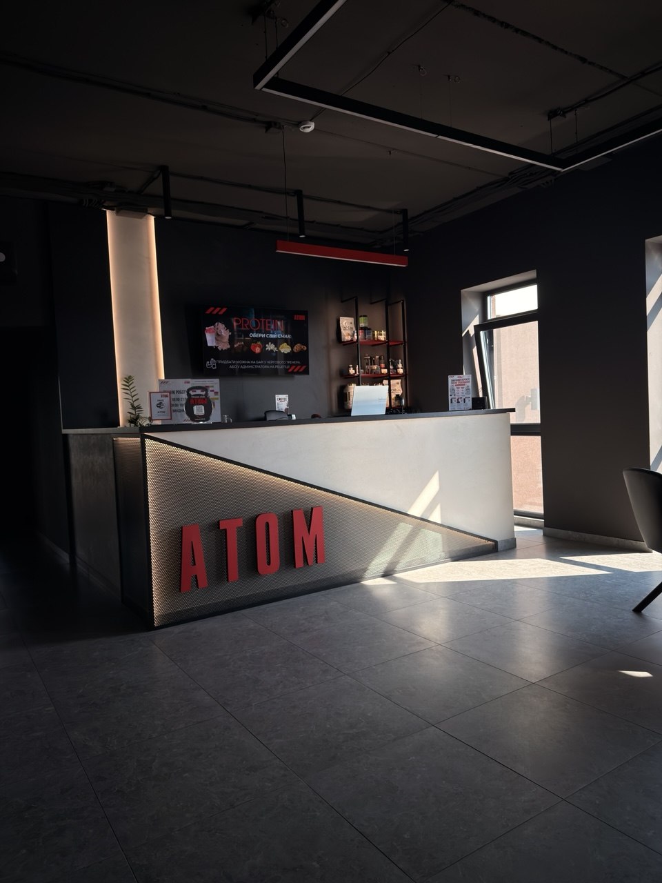 Ресепшн з підсвіченим логотипом ATOM у фітнес клубі